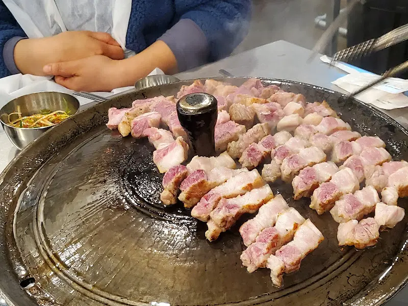 솥뚜껑 위에 가지런히 놓인 삼겹살 조각들