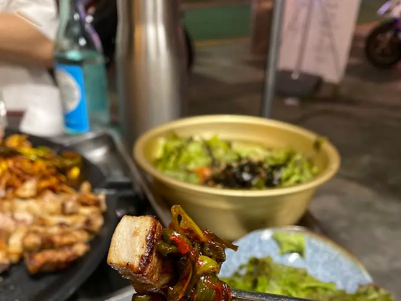 잘 구워진 삼겹살을 젓가락으로 집어 올린 모습