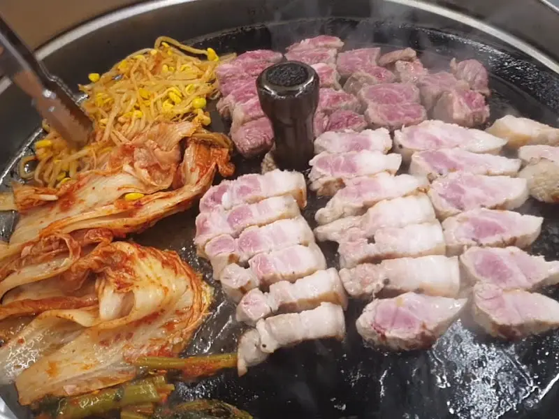 솥뚜껑에 구워지는 삼겹살과 김치