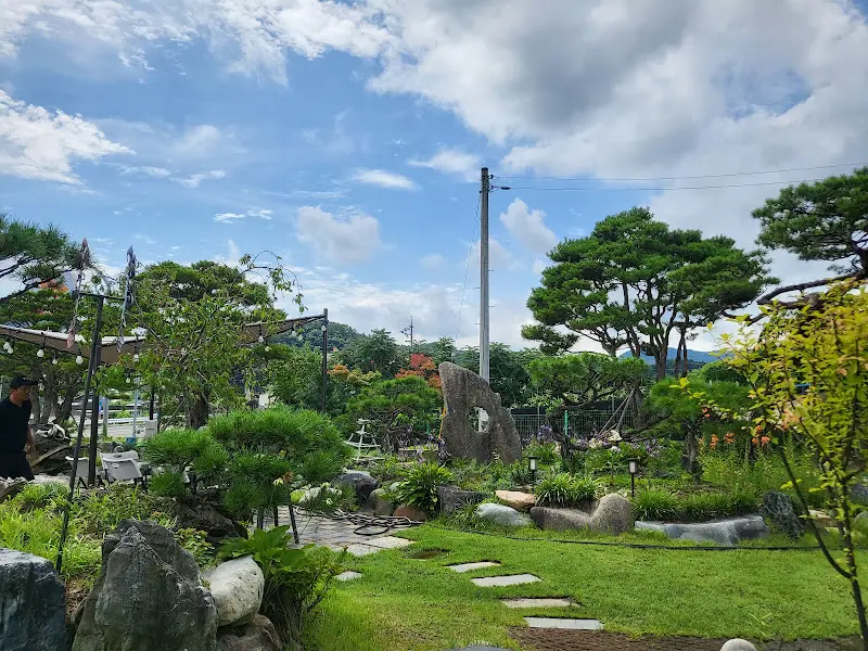 카페 정원을 담은 사진. 푸른 잔디와 나무들이 아름답게 조화를 이루고 있다.