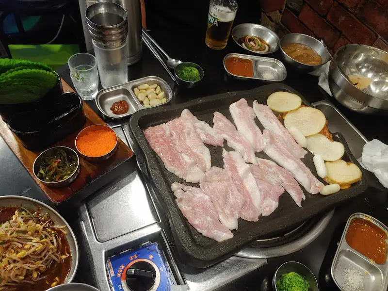 천겹살과 밑반찬이 푸짐하게 차려진 테이블