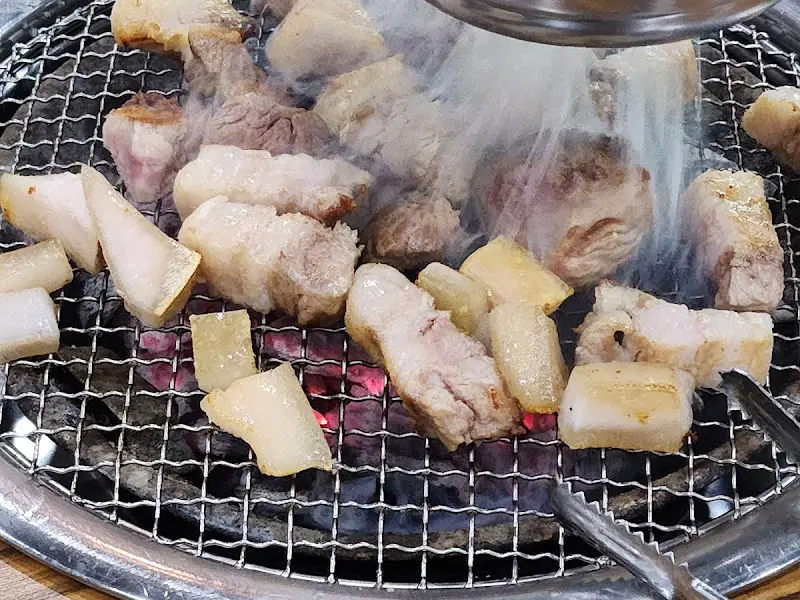 뜨거운 숯불 위에서 구워지는 흑돼지