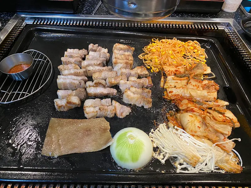 불판 위에서 익어가는 삼겹살과 김치