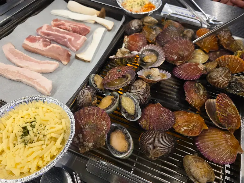 불판 위에서 익어가는 조개와 삼겹살