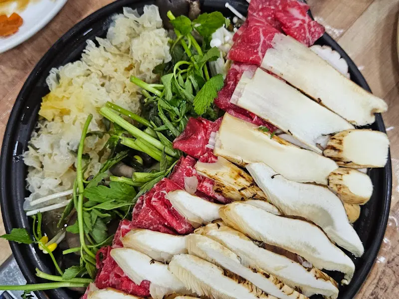 송이버섯, 소고기, 각종 채소가 푸짐하게 담긴 전골 냄비.