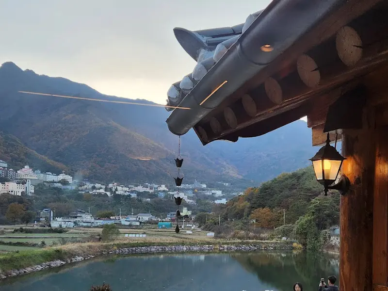 저수지와 한옥의 조화로운 풍경, 고즈넉한 분위기가 느껴진다.