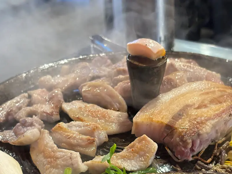 무쇠 솥뚜껑에서 익어가는 돼지고기의 모습