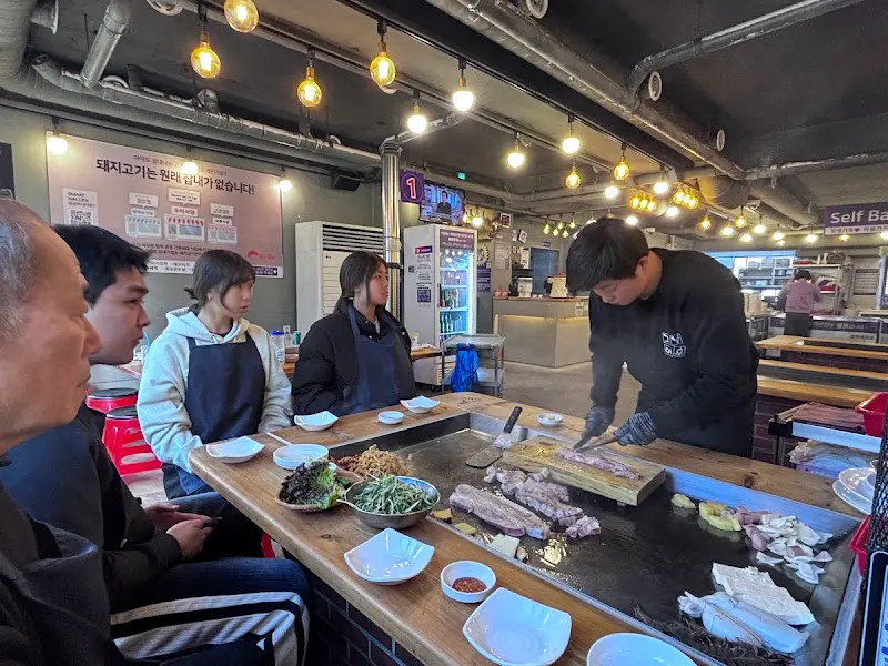 직원이 철판 위에서 고기를 굽는 모습, 능숙한 솜씨가 돋보인다.