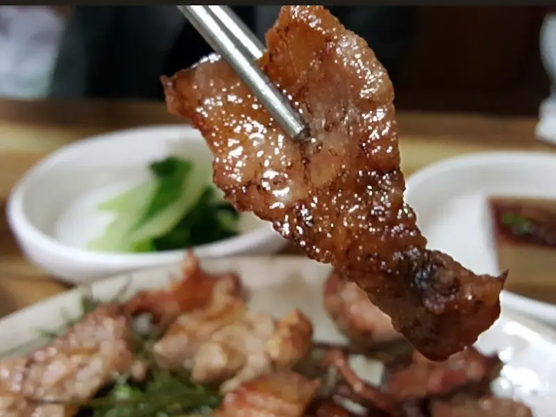 젓가락으로 집어 올린 돼지숯불구이