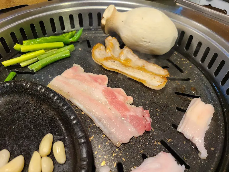 냉꽃삼겹살과 버섯, 마늘이 함께 구워지는 모습