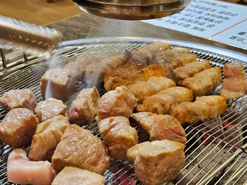 숯불 위에서 맛있게 구워지고 있는 두툼한 삼겹살과 목살