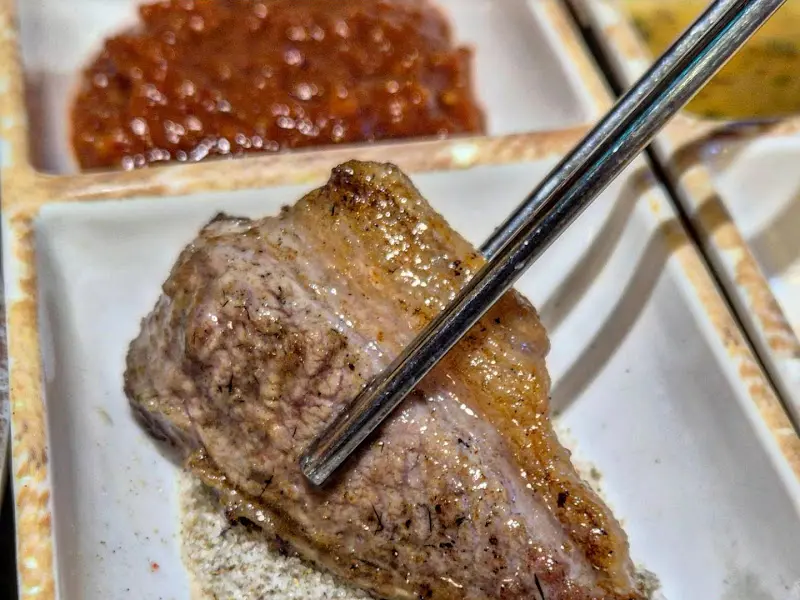 잘 구워진 고기를 소금에 찍어먹는 모습