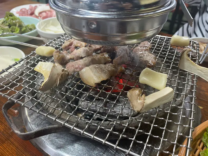 숯불 위에서 구워지는 삼겹살과 버섯