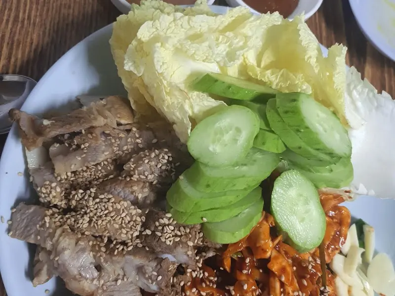 보쌈 위에 윤기가 흐르고 그 위에 깨가 뿌려져 있어 먹음직스러운 모습