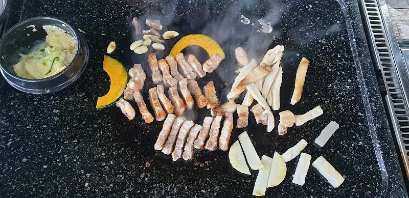 불판 가득 채워진 삼겹살, 해산물, 채소