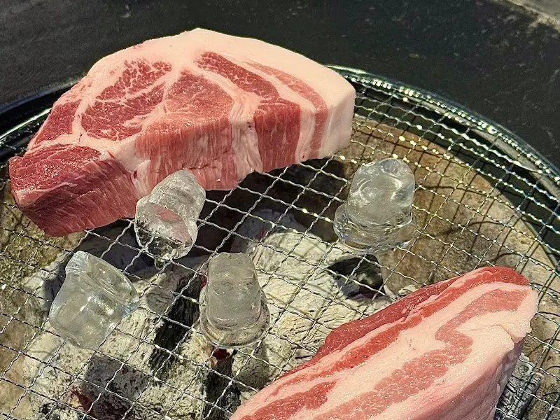 두툼한 삼겹살이 숯불 위에 놓여 있는 모습