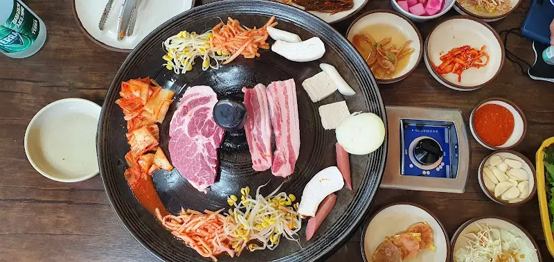 다채로운 밑반찬과 삼겹살이 함께 놓인 식탁