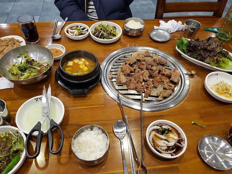 푸짐하게 차려진 테이블, 초벌구이 갈비와 다양한 반찬들이 놓여있다.