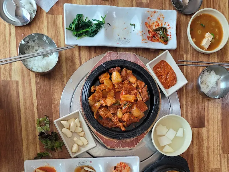 불판 위에서 익어가는 삼겹살과 주변에 놓인 다양한 반찬들