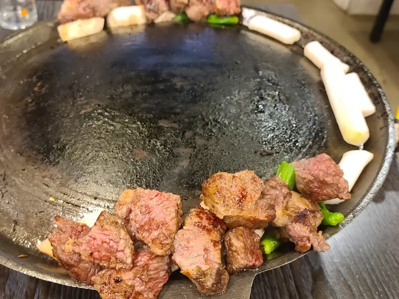 불판 위에 구워진 고기, 버섯, 떡