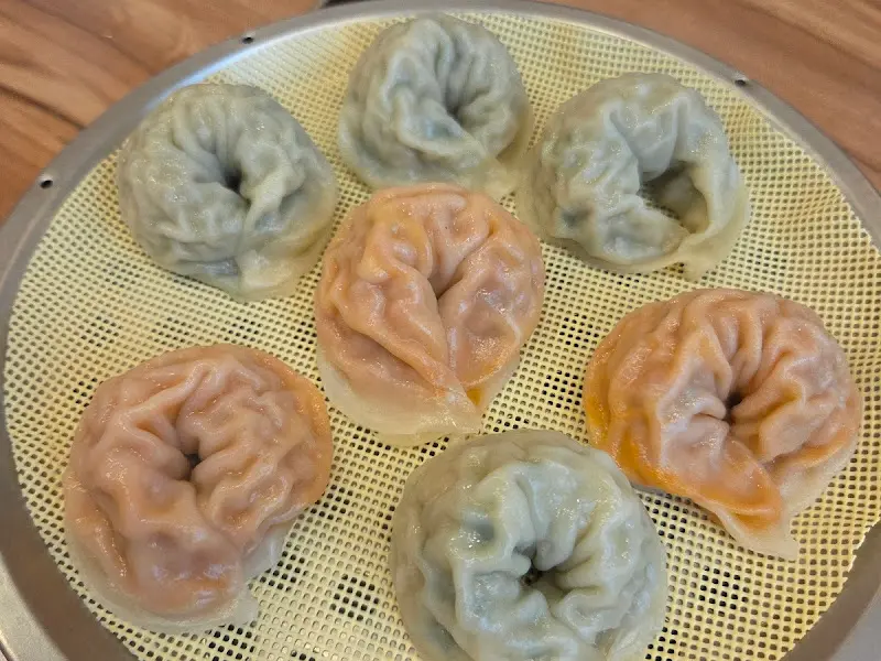 김이 모락모락 나는 찜기에 가지각색의 만두들이 담겨있다.