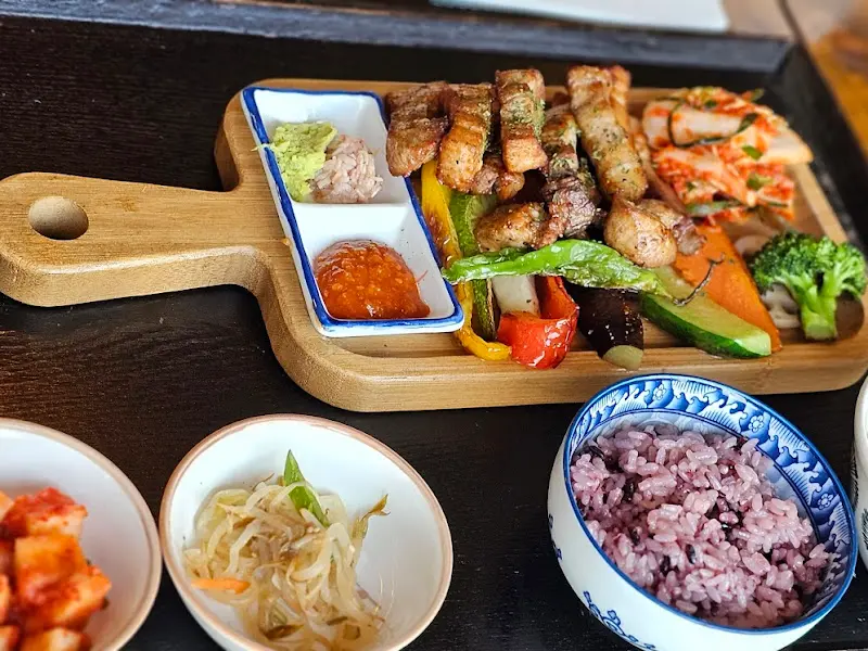 나무 도마 위에 정갈하게 담긴 삼겹살 구이와 채소 구이