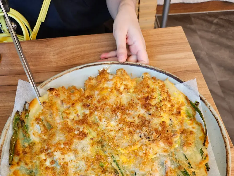 접시에 담긴 땡초 부추전을 젓가락으로 집고 있는 모습이다.