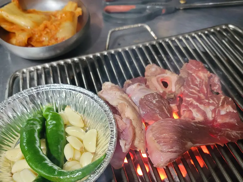 불판 위에서 익어가는 고기와 김치, 마늘