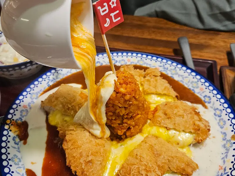 엑스포 타워 돈까스에 치즈 퐁듀를 뿌리는 모습