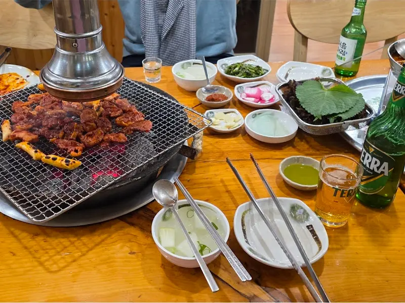 숯불 위에서 익어가는 양념 오리구이와 밑반찬