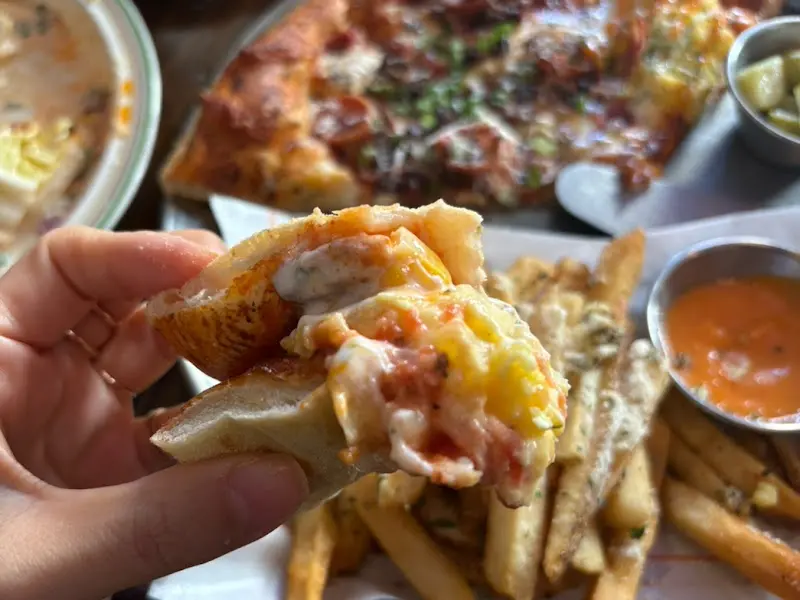 에그 포테이토 피자 조각을 손으로 들고 있는 모습