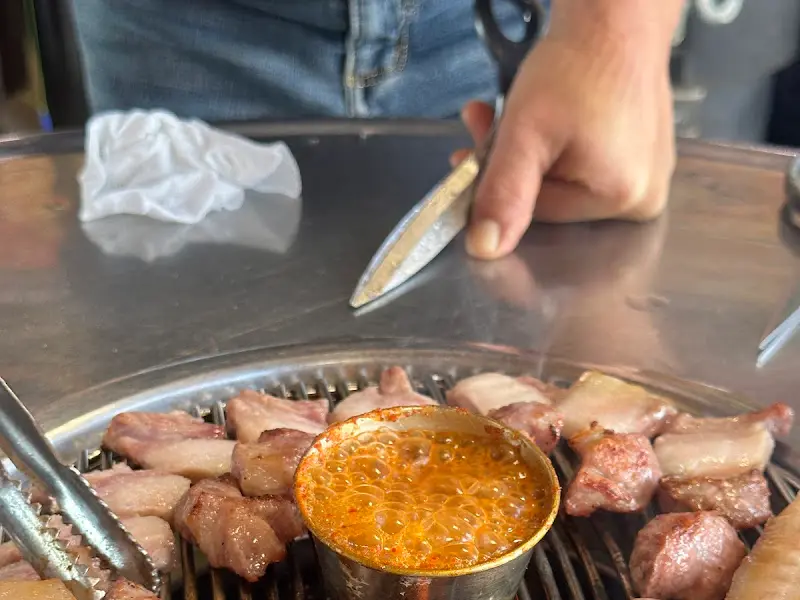 불판 한켠에 놓인 멜젓이 연탄불에 끓고 있는 모습