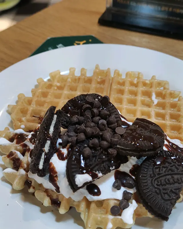 와플 위에 생크림, 초콜릿 시럽, 오레오 쿠키를 듬뿍 올린 모습