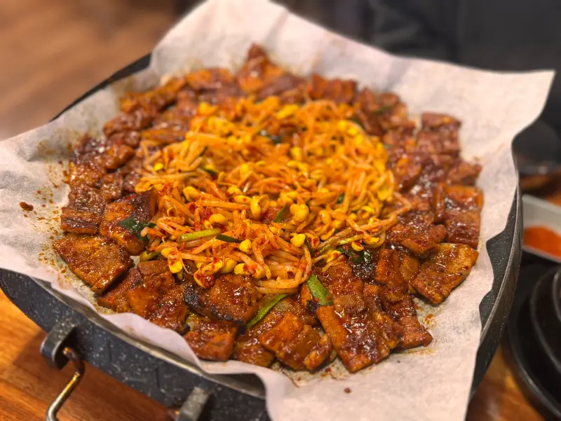 철판 위에 푸짐하게 담겨 있는 고추장 삼겹살의 모습