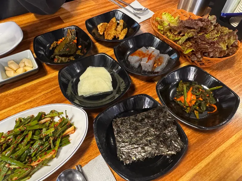 다채로운 밑반찬이 정갈하게 담겨 테이블 위에 놓여 있는 모습