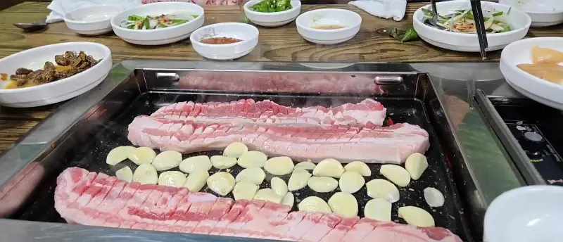 불판 위에서 익어가는 목살과 마늘