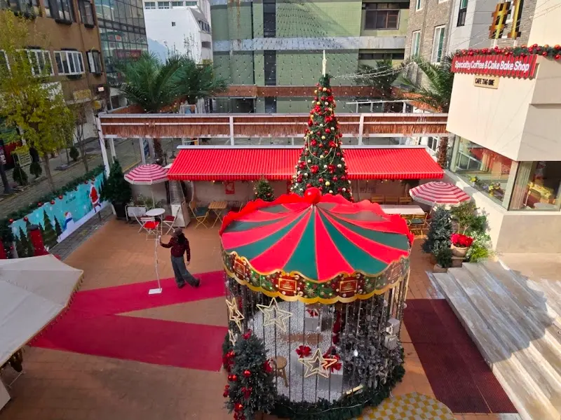 카페 앞마당에 설치된 회전목마 모형 사진. 크리스마스 장식과 어우러져 동화 같은 분위기를 연출한다.