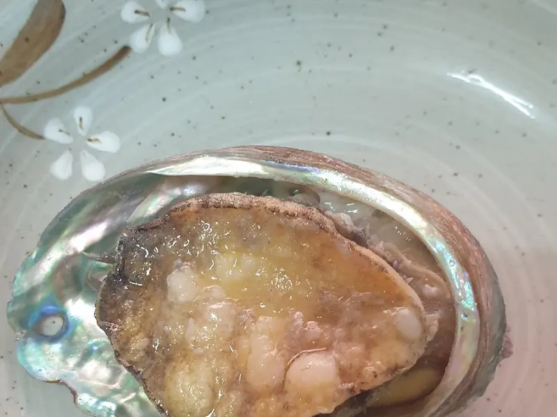 전복 껍데기 위에 올려진 전복 요리의 모습