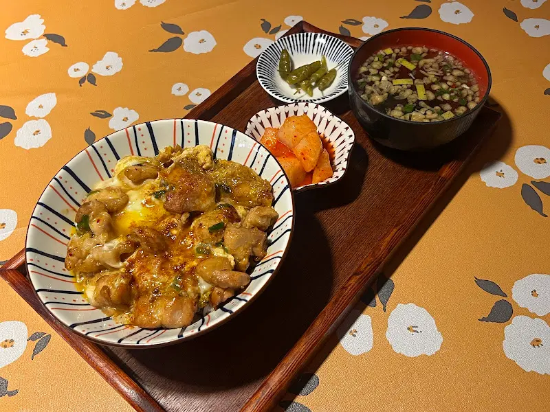 나무 쟁반 위에 정갈하게 담겨 나온 오야꼬동 한 상 차림. 곁들임 반찬으로 단무지와 고추 장아찌, 따뜻한 국물이 함께 제공된다.