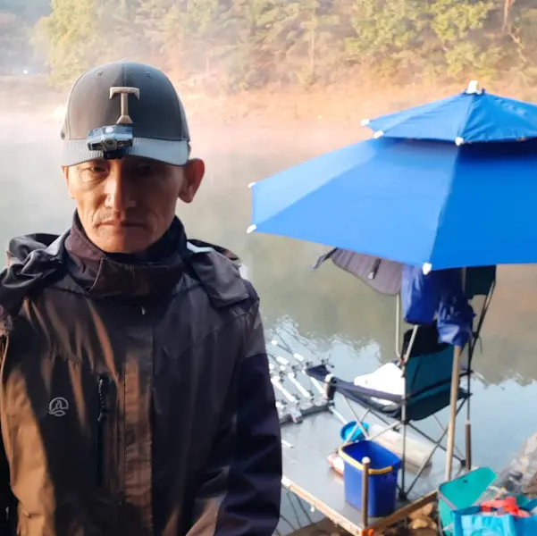 낚시하는 사람의 뒷모습, 잔잔한 호수와 몽환적인 새벽 안개가 인상적이다.