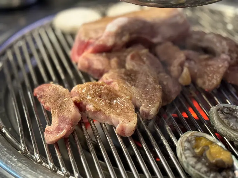 숯불 위에서 노릇하게 익어가는 고기와 전복