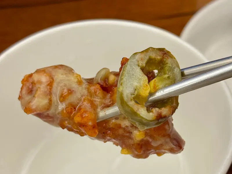 젓가락으로 집은 닭강정과 할라피뇨