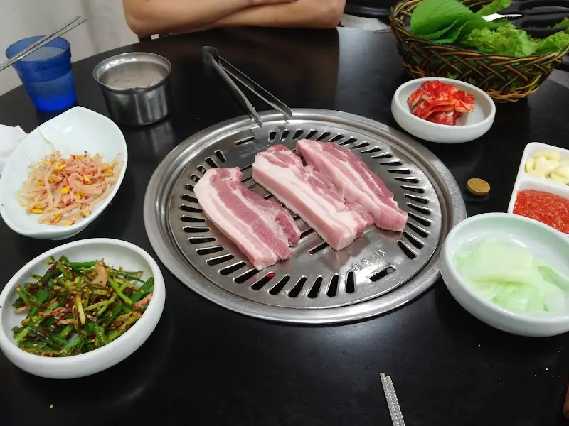 불판 위의 삼겹살과 푸짐한 밑반찬