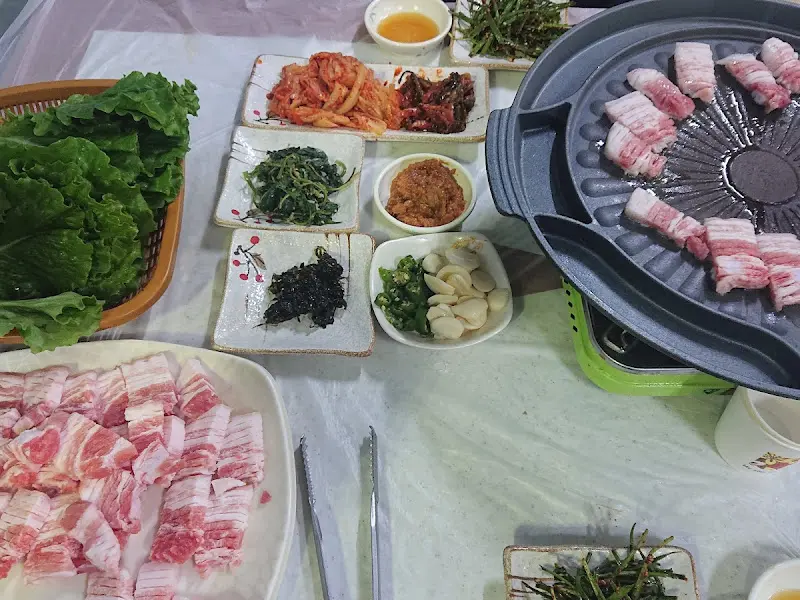 삼겹살과 함께 다양한 반찬들이 놓여 있는 테이블 전경