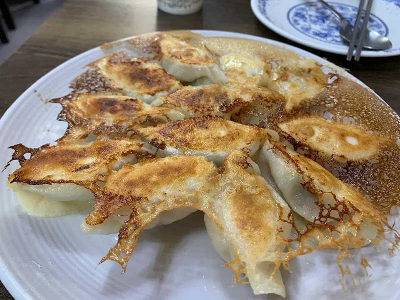 빙화만두 한 접시가 테이블 위에 놓여있다. 만두 밑부분은 바삭하게 구워져 있고, 윗부분은 촉촉해 보인다.