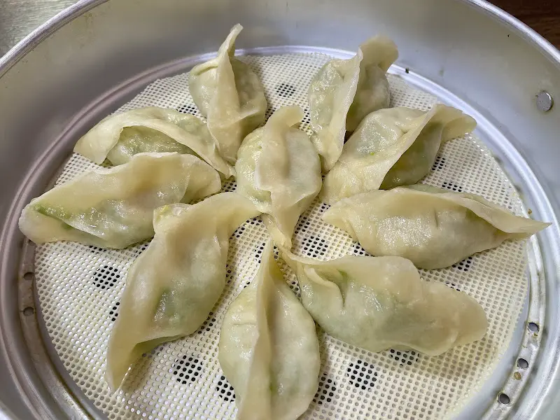 찜통 안에는 초록색 속이 비치는 만두들이 가지런히 놓여 있다.