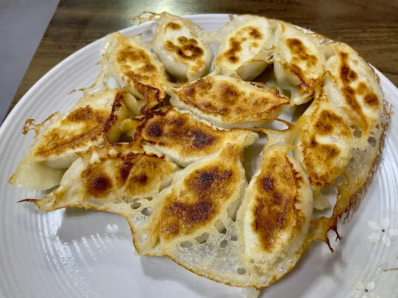 접시에 담긴 빙화만두는 바닥이 노릇하게 구워져 있으며, 가장자리에는 섬세한 튀김 그물망이 형성되어 있다.