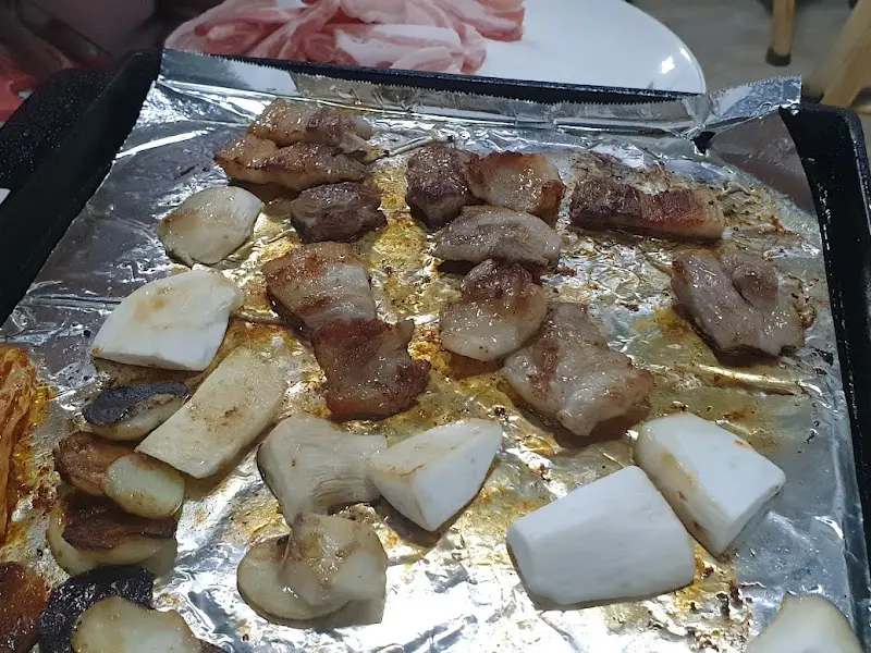 지글지글 익어가는 냉동 삼겹살과 김치, 마늘