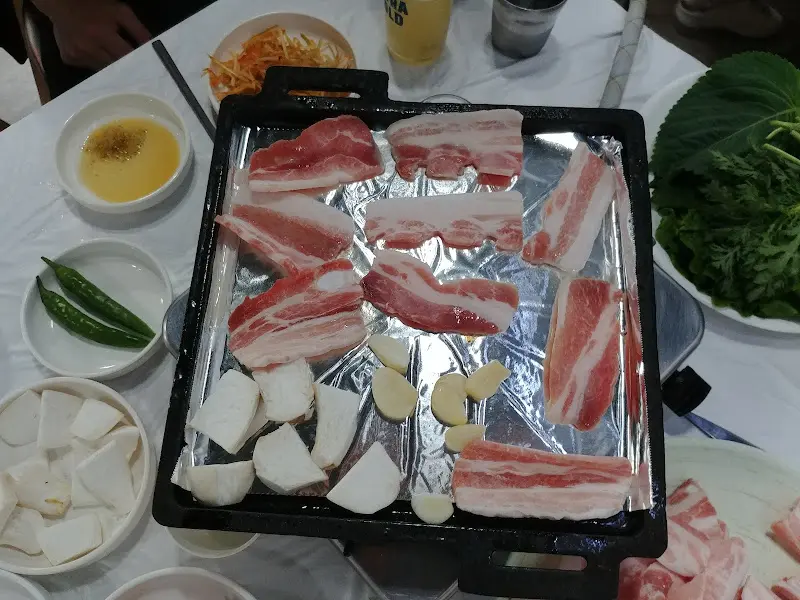 불판 위에서 익어가는 삼겹살, 김치, 마늘, 그리고 버섯