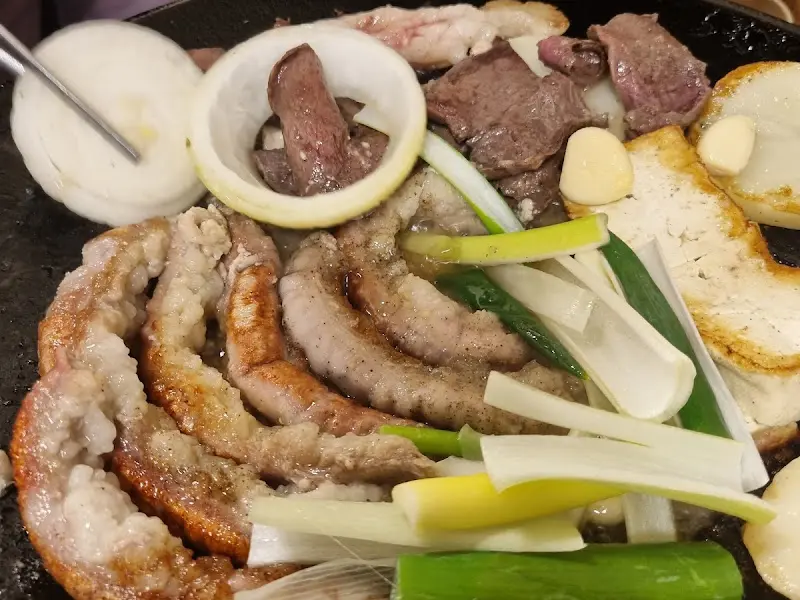 불판 위에 곱창, 대창, 막창, 양파, 감자, 마늘 등이 함께 구워지고 있는 모습